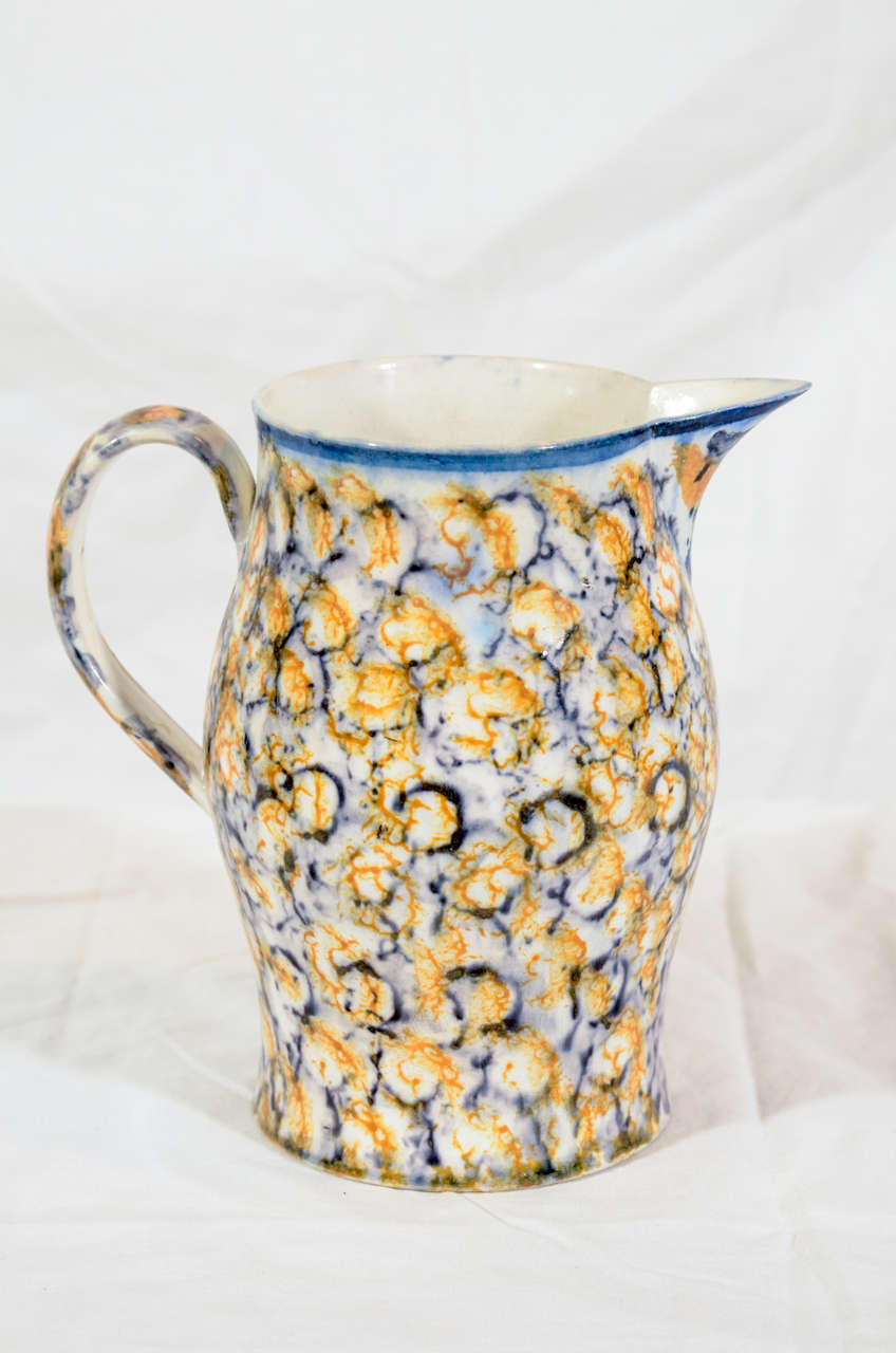 A late 18th century pearlware pottery jug with a sponged glaze. Spongeware was made by applying colored oxides to the pottery piece.The potter dipped a piece of sponge into a colored glaze and then dabbed this over the surface.This jug was colored
