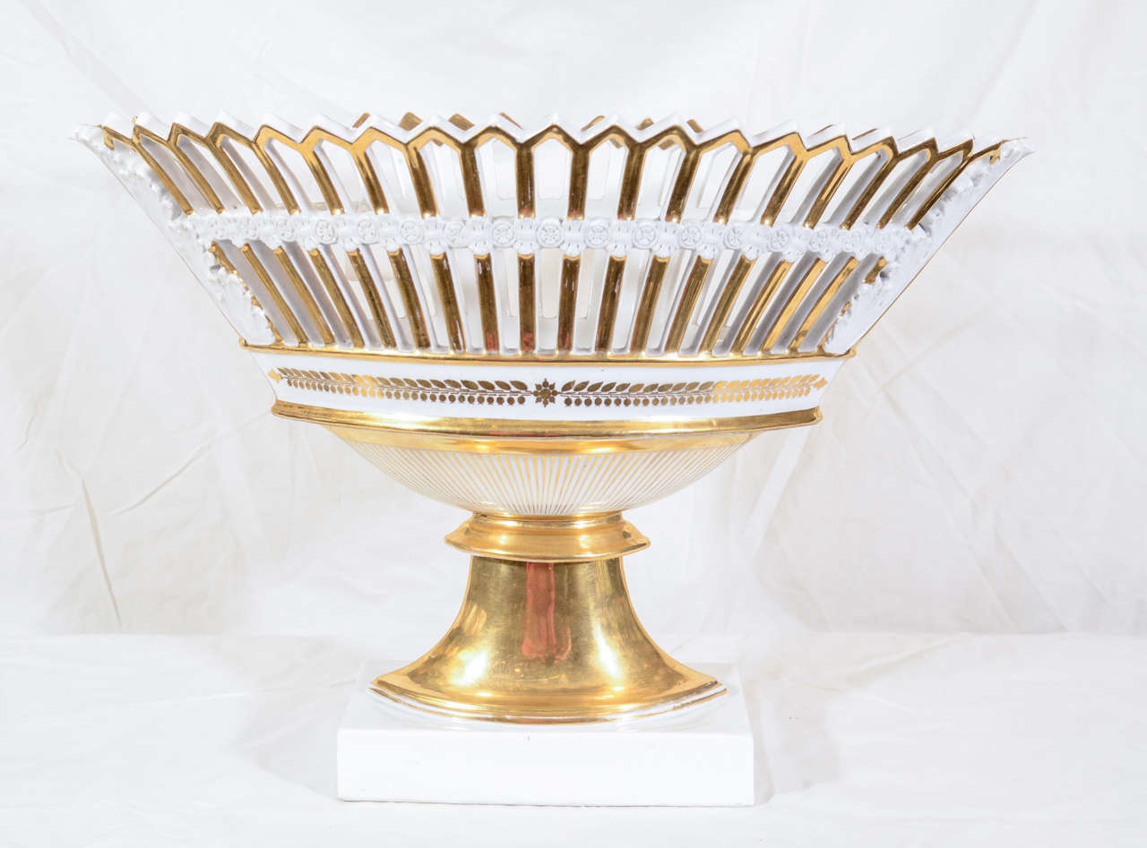 An elegant Paris Porcelain basket (corbeille) heavily gilded, oval shaped, and pierced, with two bands of white porcelain.   The basket stands on a white porcelain rectangular plinth.