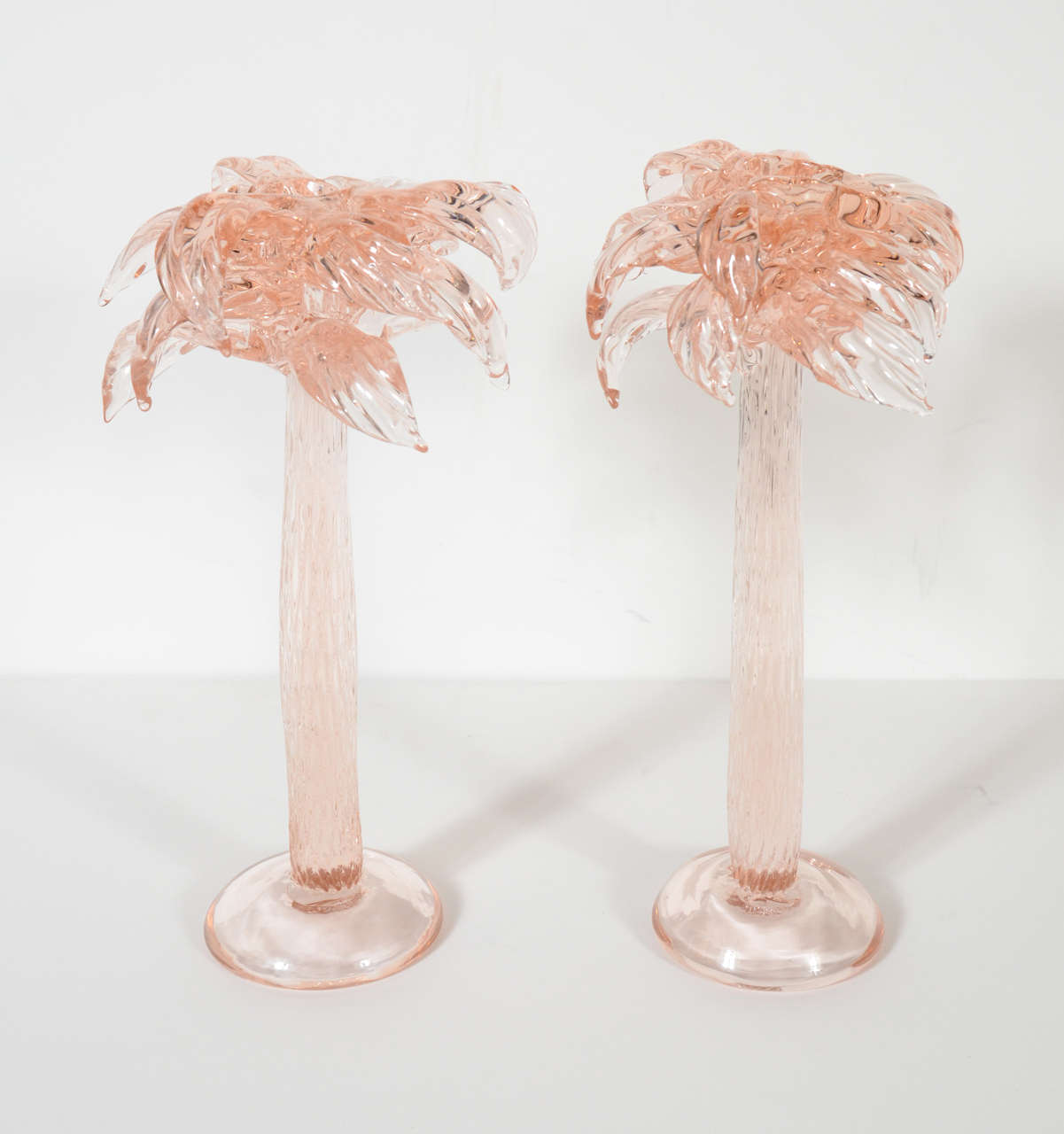 This stunning candleholders are hand blown Rose colored murano glass and features stylized palm trees blowing .