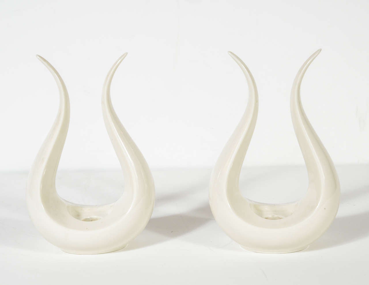 This elegant pair of candle stands feature a symmetrical and gracefully tapered lyre form. They were designed by the renowned ceramic producer Lenox and realized in bone white porcelain. They are in excellent condition. They are inscribed on the
