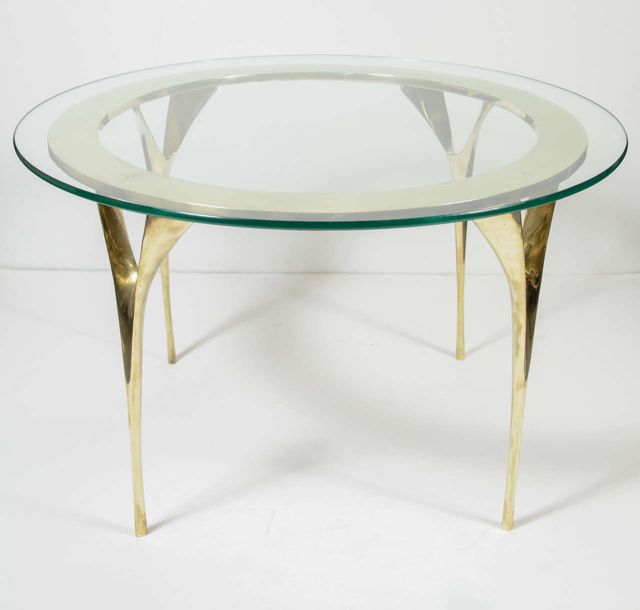 This chic Modernist cocktail table features fine stiletto legs around a brass rim and glass top.Really beautifully made and executed.