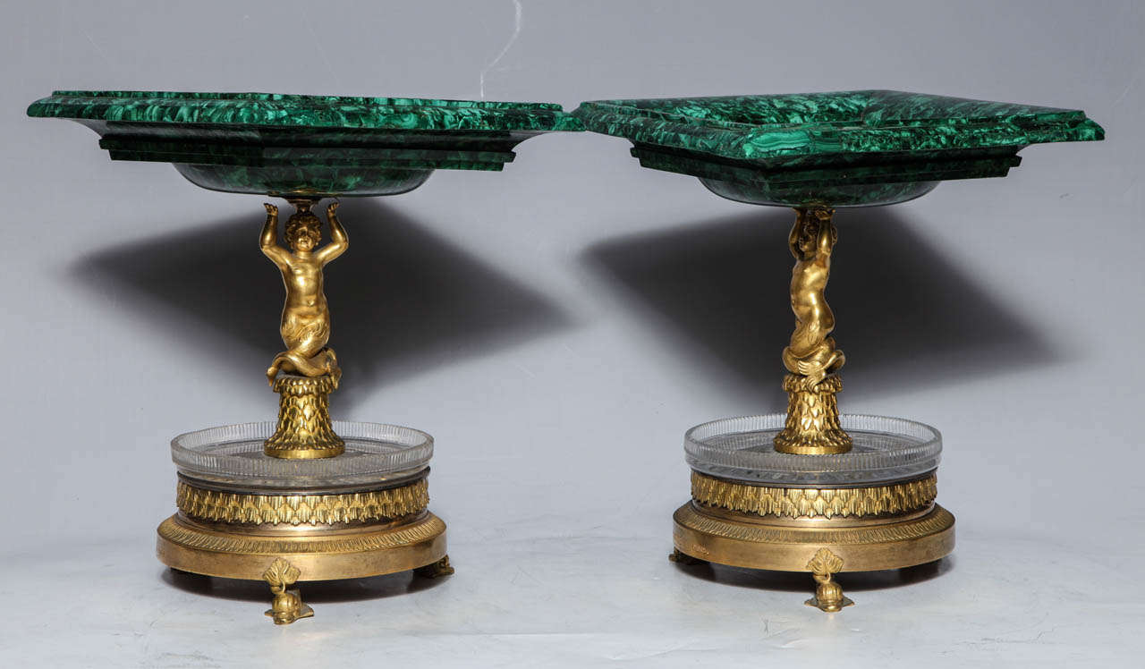 A magnificent pair of Russian Empire Period malachite, French doré bronze and cut crystal Tazzas, signed THOMIRE A PARIS. The square malachite bowls are upheld by putti (cupids) standing on tree trunks. The lower levels are formed by cut crystal