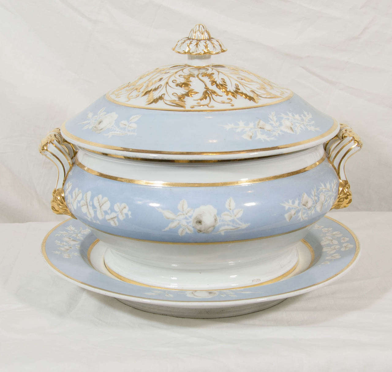 A standout Worcester soup tureen and stand painted baby blue and decorated with white roses, further decorated on the cover with outstanding gold gilding which also covers the finial and the handles. The tureen was made in England circa 1820 by