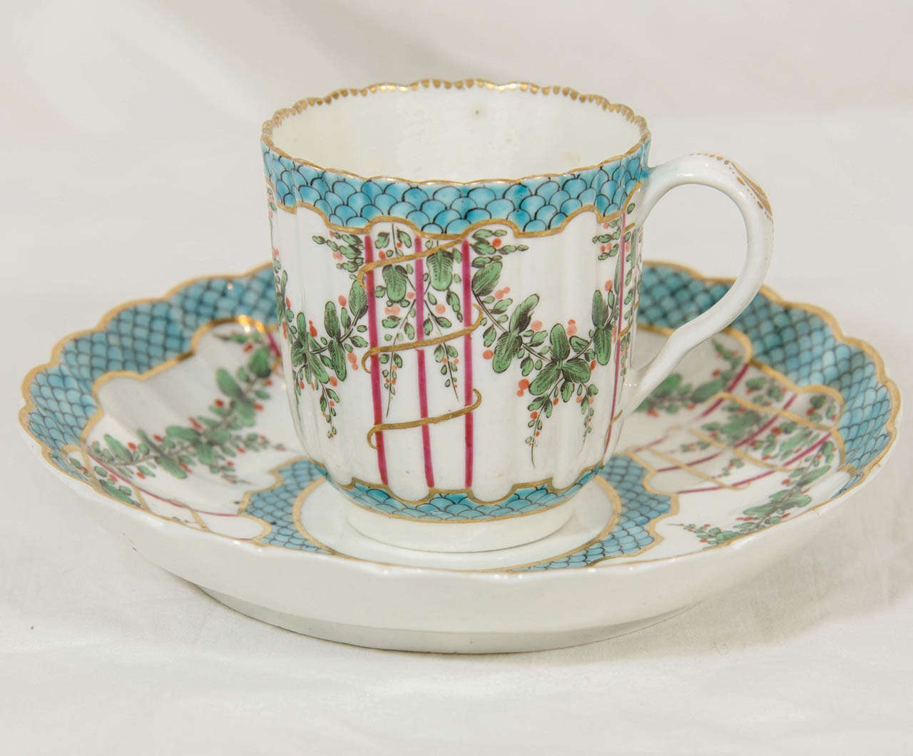 A very fine 18th century Dr. Wall Worcester soft-paste porcelain coffee cup and saucer,of fluted form in the Sevres style, painted in overglaze colored enamels in a version of the 'Hop Trellis' pattern.
With a turquoise central border enclosing a