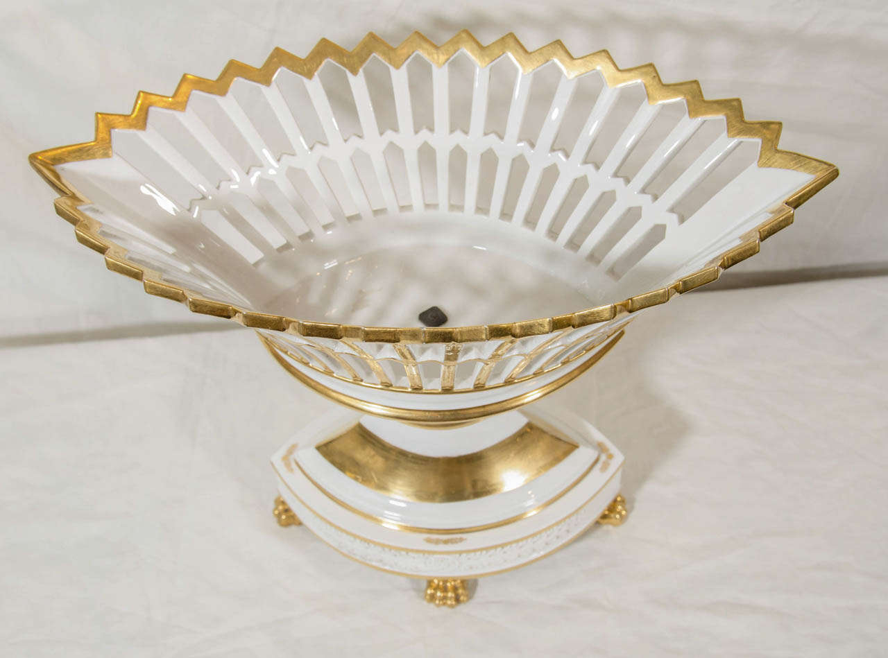 An elegant and dramatic Paris Porcelain gilded basket, oval shaped and pierced,  with bands of bright white porcelain. The basket stands on four gilded lion's paw feet.