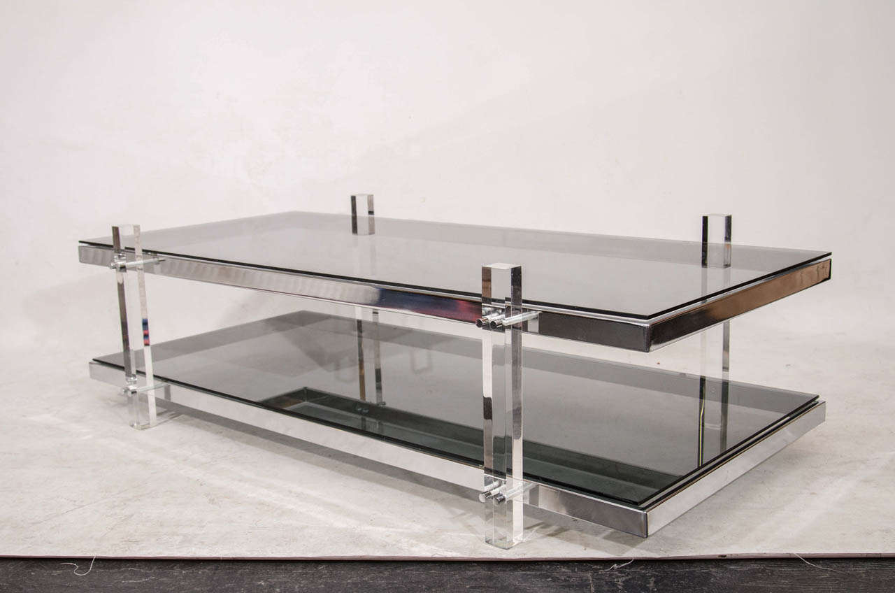 Very beautiful, two tiered coffee table with a chrome frame, lucite supports, smoke tinted glass and accented with chrome studs. Please contact for location.