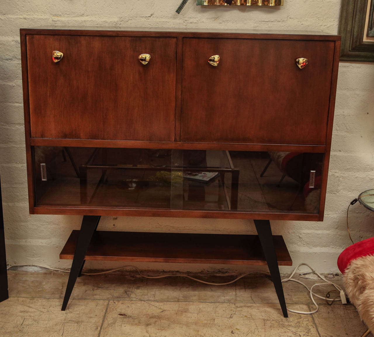 An amazing 1950s Italian dry bar or cabinet. Left door opens to a serving platform which can also be used a writing desk. Right side is for storage. Two sliding glass doors at the bottom for additional storage. Brass handles.