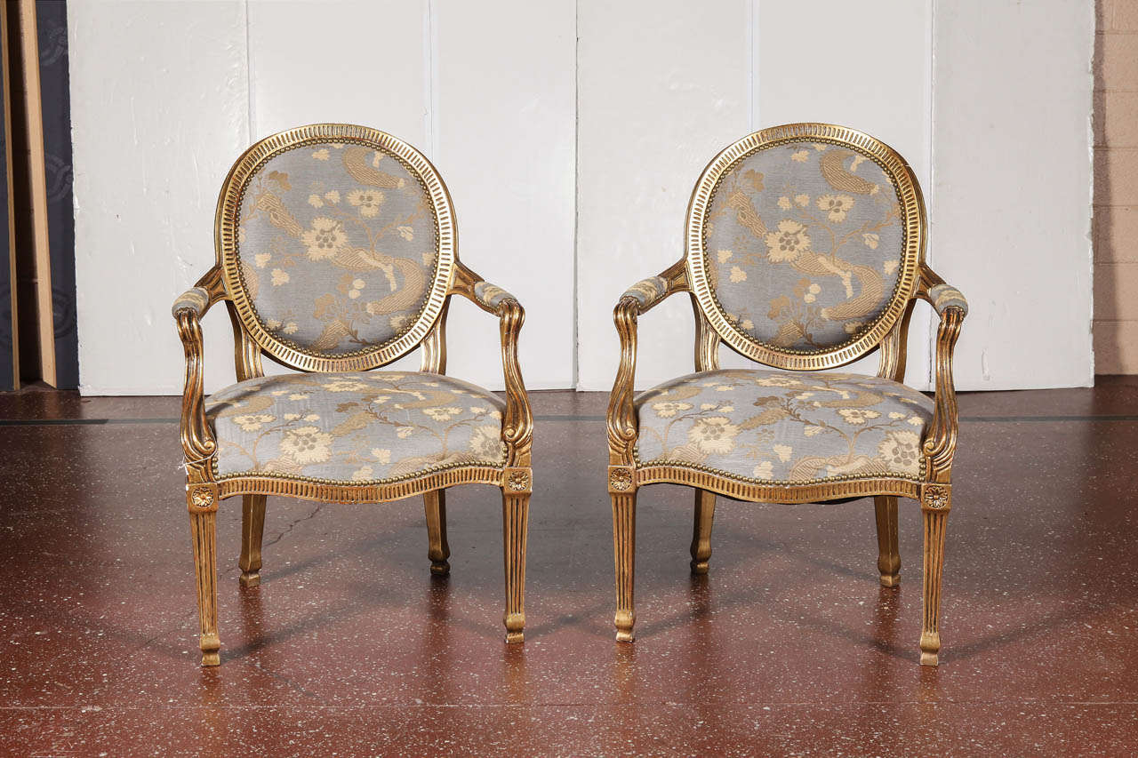 Pair of giltwood Louis XVI style armchairs with round back, blue upholstery.