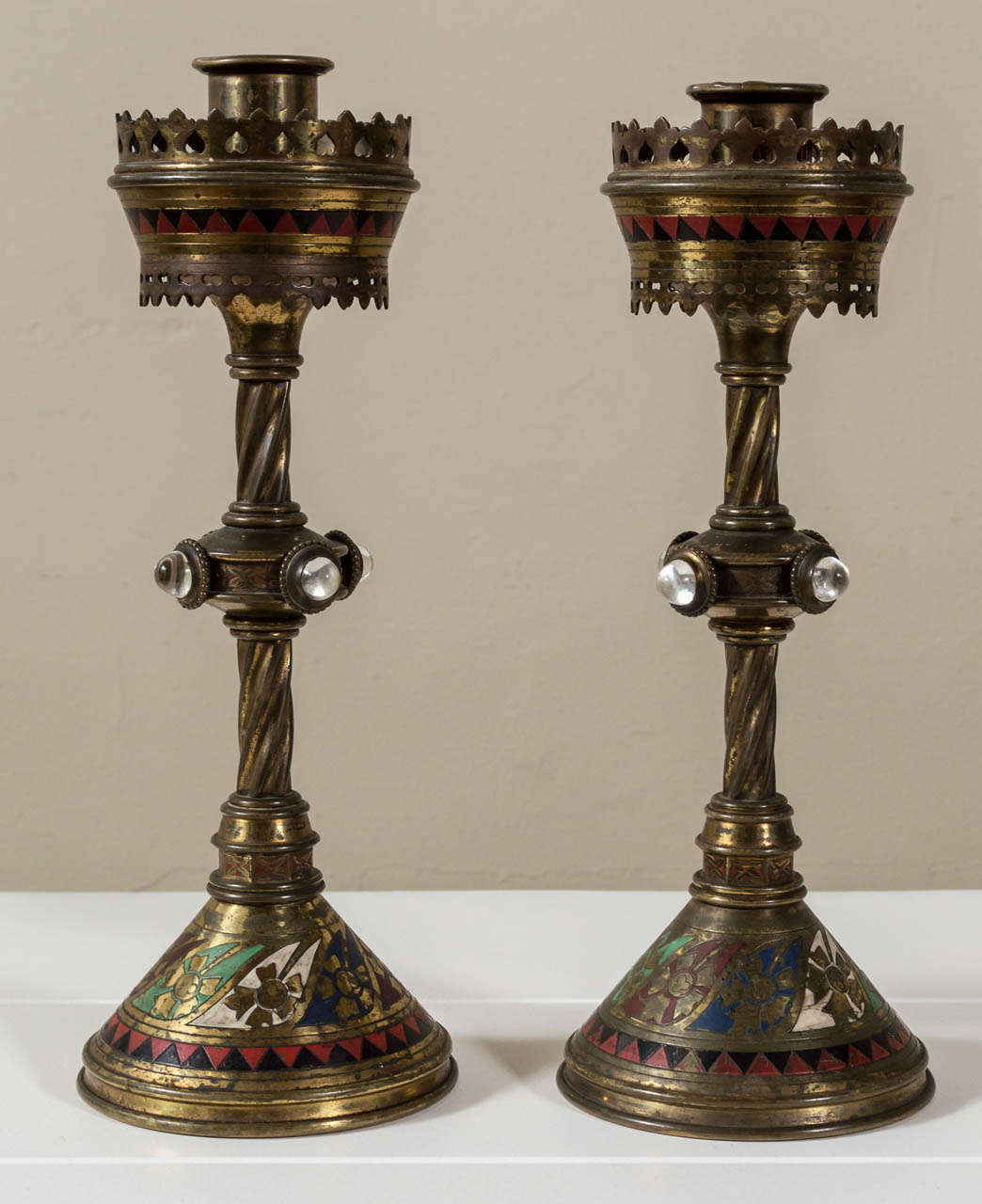 A rare and unusual pair of brass, glass and enamel candlesticks