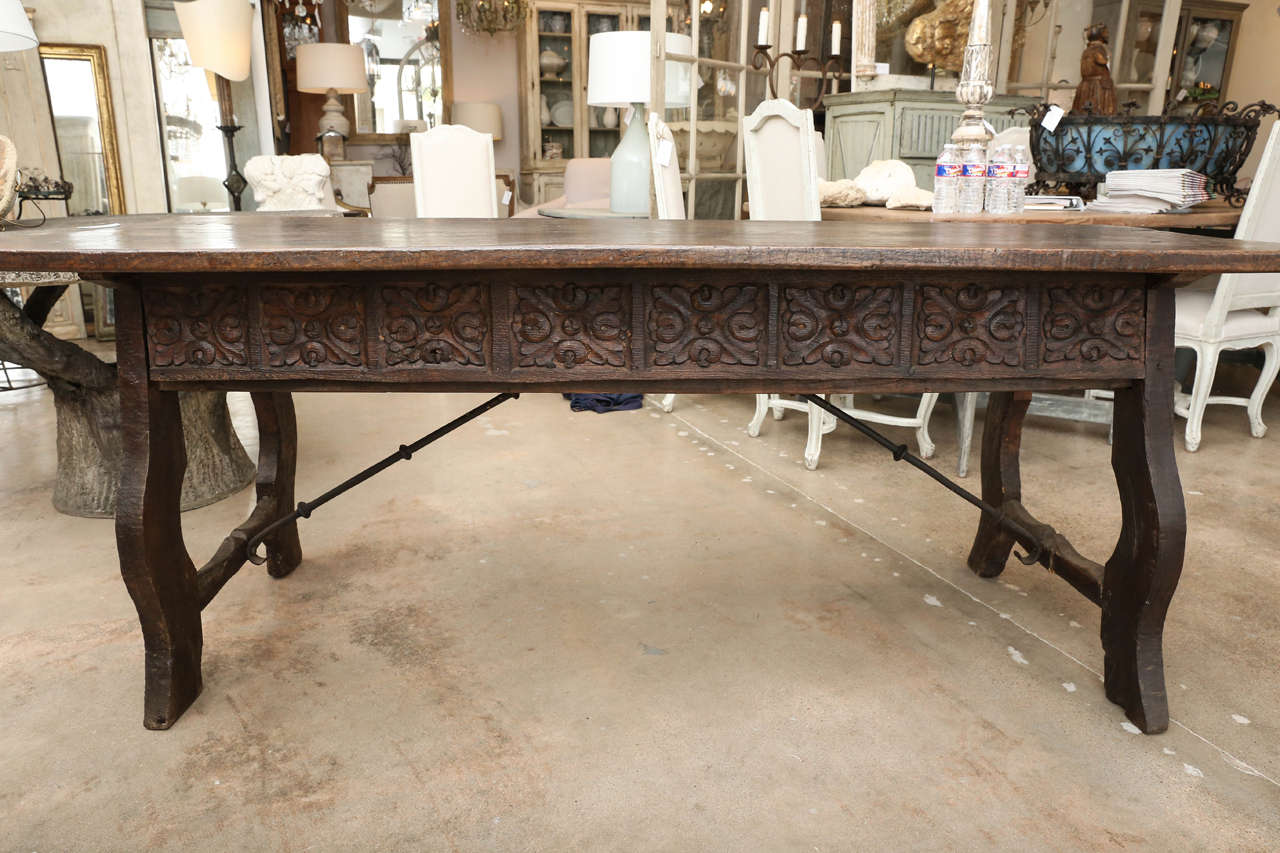 Late 17th century Baroque period carved chestnut Spanish table with a single plank thick top, rich patina, decorative iron stretcher and four drawers.