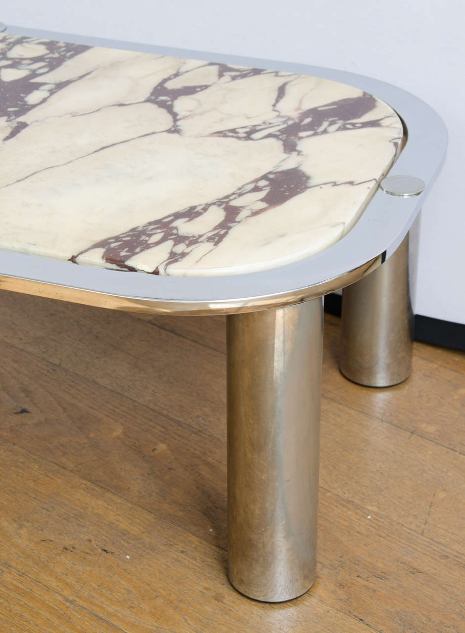 Rectangular coffee table with curved corners and chrome tubular legs. The top is inset with beautiful and richly patterned cream and red marble.