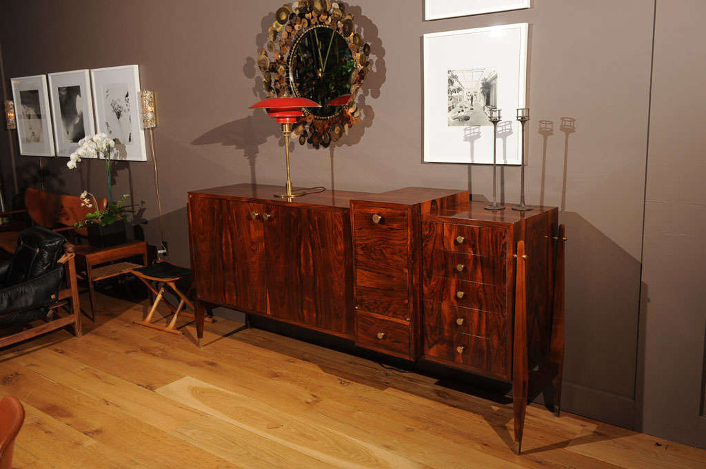 Important rosewood veneer sideboard composed of three casings, one opening onto shelves in sycamore, one opening by five drawers and the central one opening by a flap onto an illuminating bar.