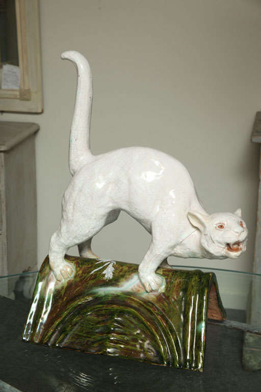 A Normande “Brevet” white cat standing on a green roof gable tile