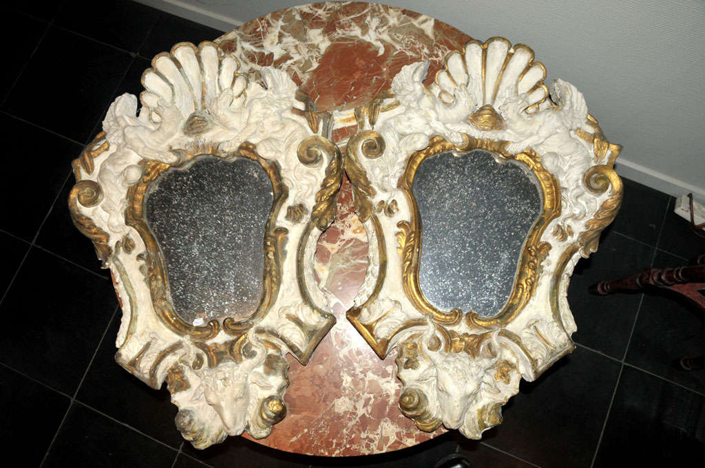 A pair of antique Italian wood and gesso mirrors, decorated with griffins and rams heads, partially gilt (gold leaf), the old mirror glass is nicely weathered.

h 73 x w 52 x d 8 cm