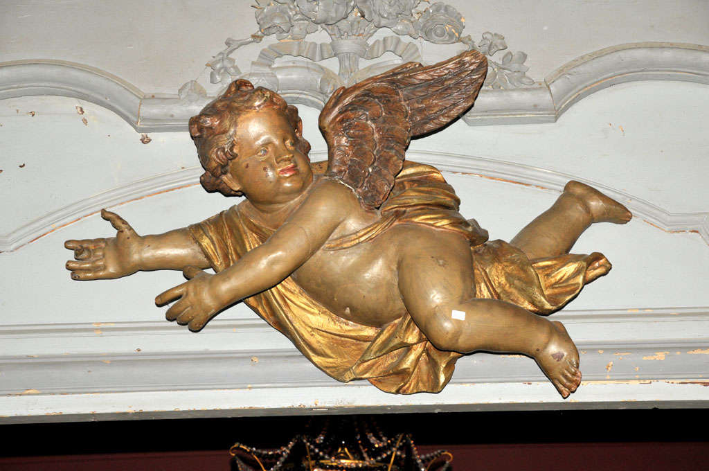 An 18th century French Baroque parcel gilt and polychrome painted carved putto