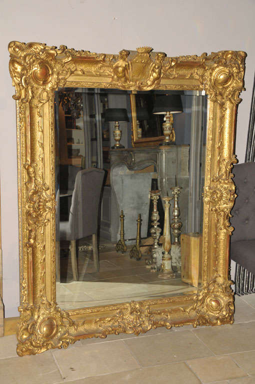 A large 19th century French giltwood mirror, the bevelled mirror plate within a richly decorated frame, crested by a coat of arms.