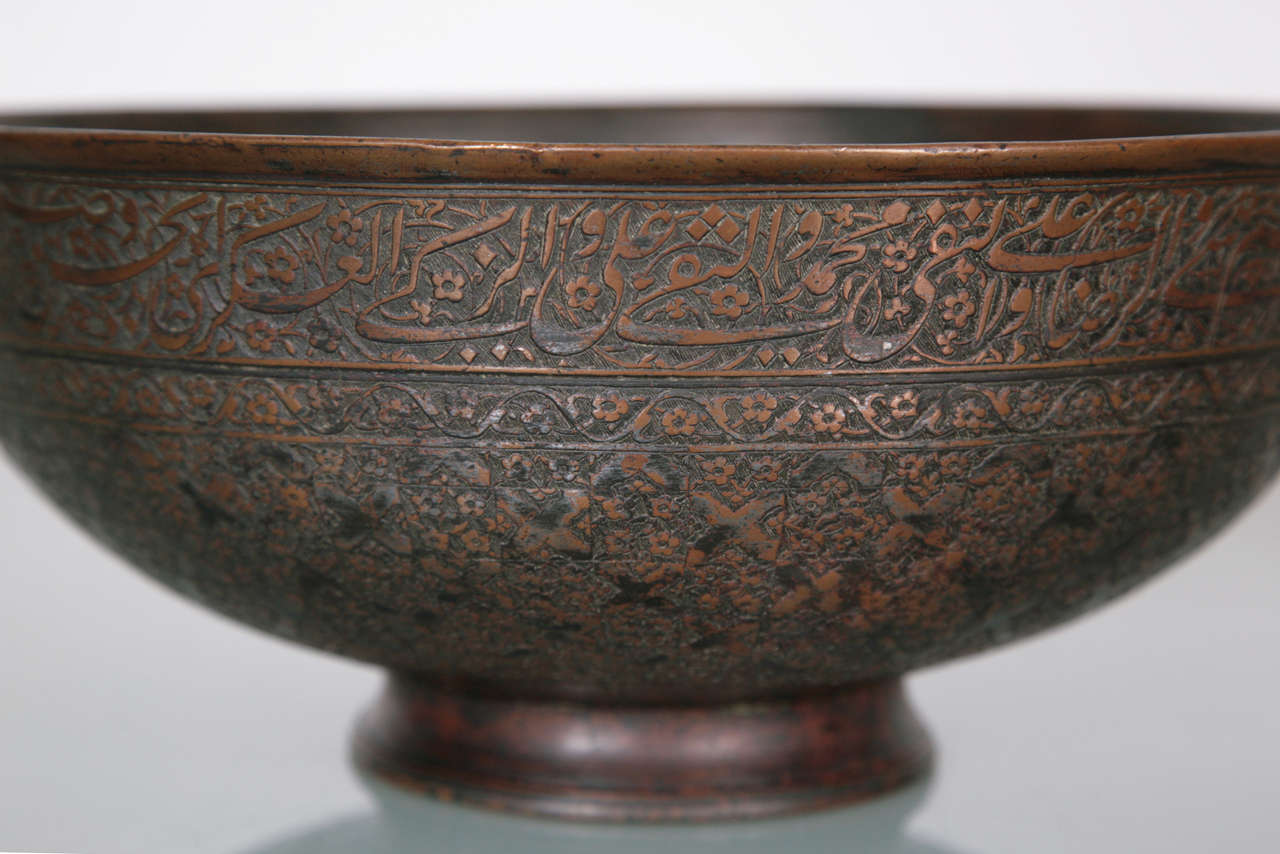 Engraved with a register of calligraphy below the rim and the rest of the body covered with elegant floral sprays intersected by cross motifs. A band of elegant trefoil design above the foot.