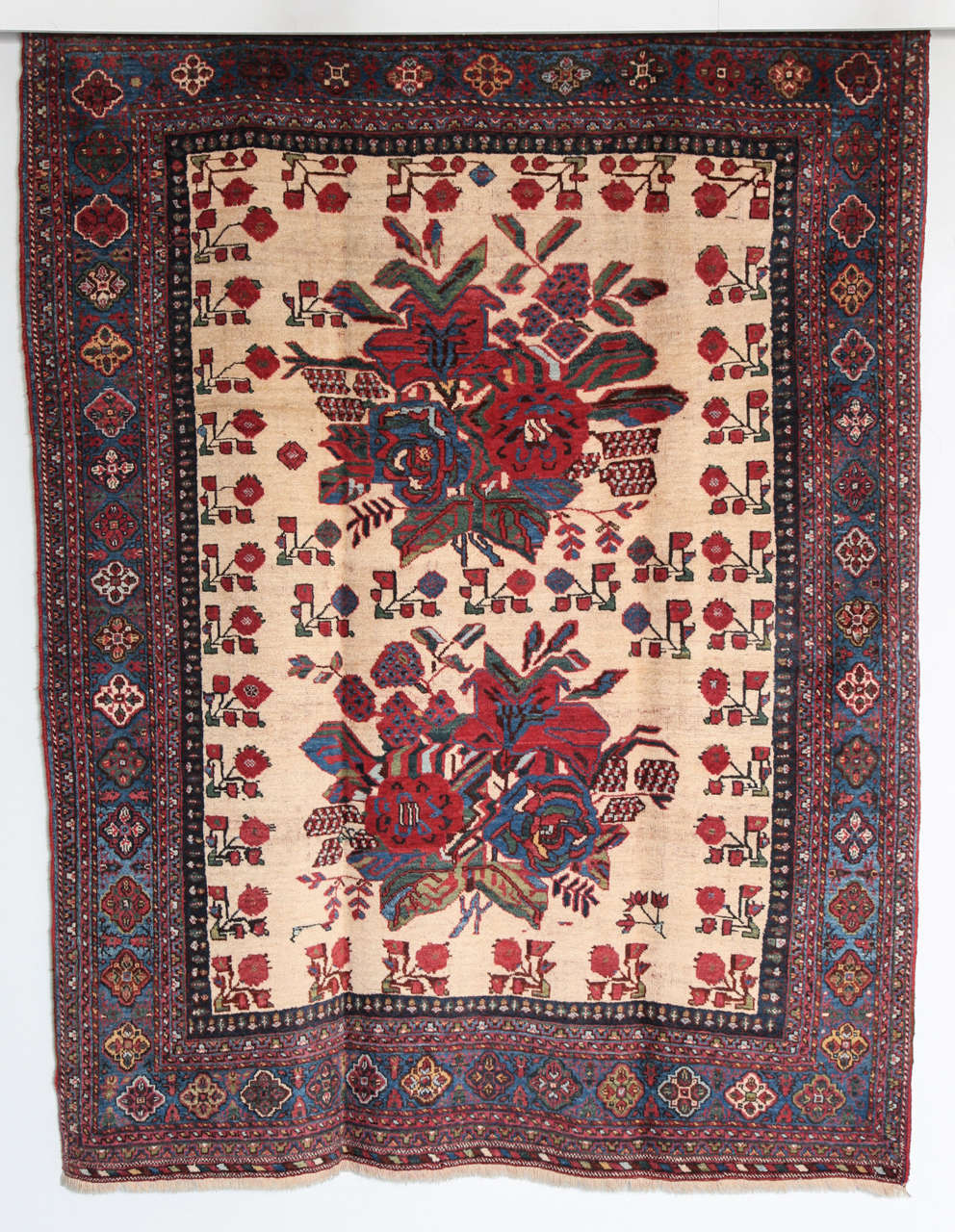 This Persian Afshar carpet circa 1890 consists of a hand-knotted handspun wool pile and natural vegetable dyes. It is a marriage carpet from the village of Heriz and features two central bouquets of flowers in red, blue and green amid a bright cream