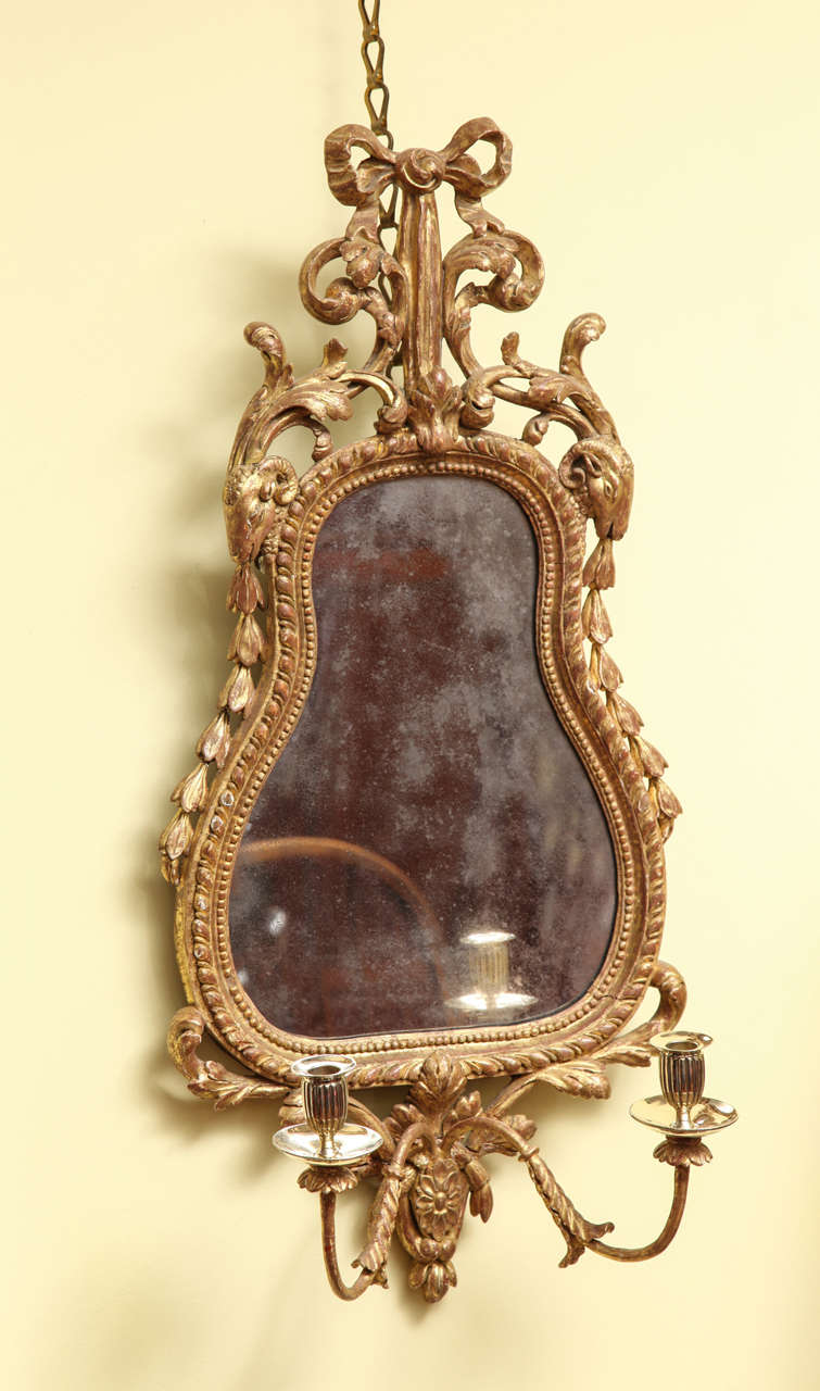 Very fine antique Chippendale period carved giltwood two-light Girandole in the Adam style, the gadrooned and bead carved cartouche shaped frame with tied ribbon top and ram's head's trailing husk carving, above a central paterae issuing twin