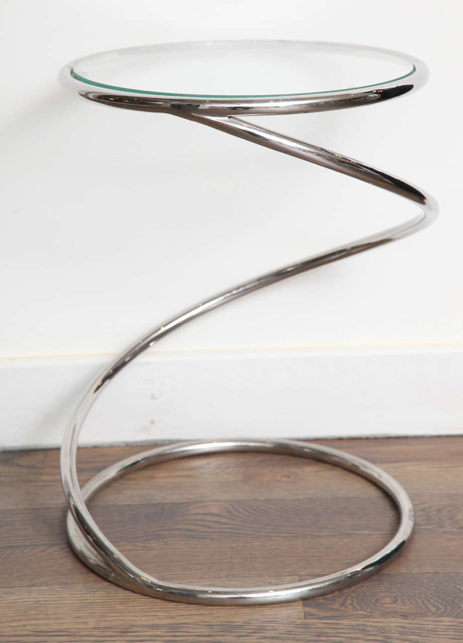 A small pair of tubular chrome side tables with glass tops.