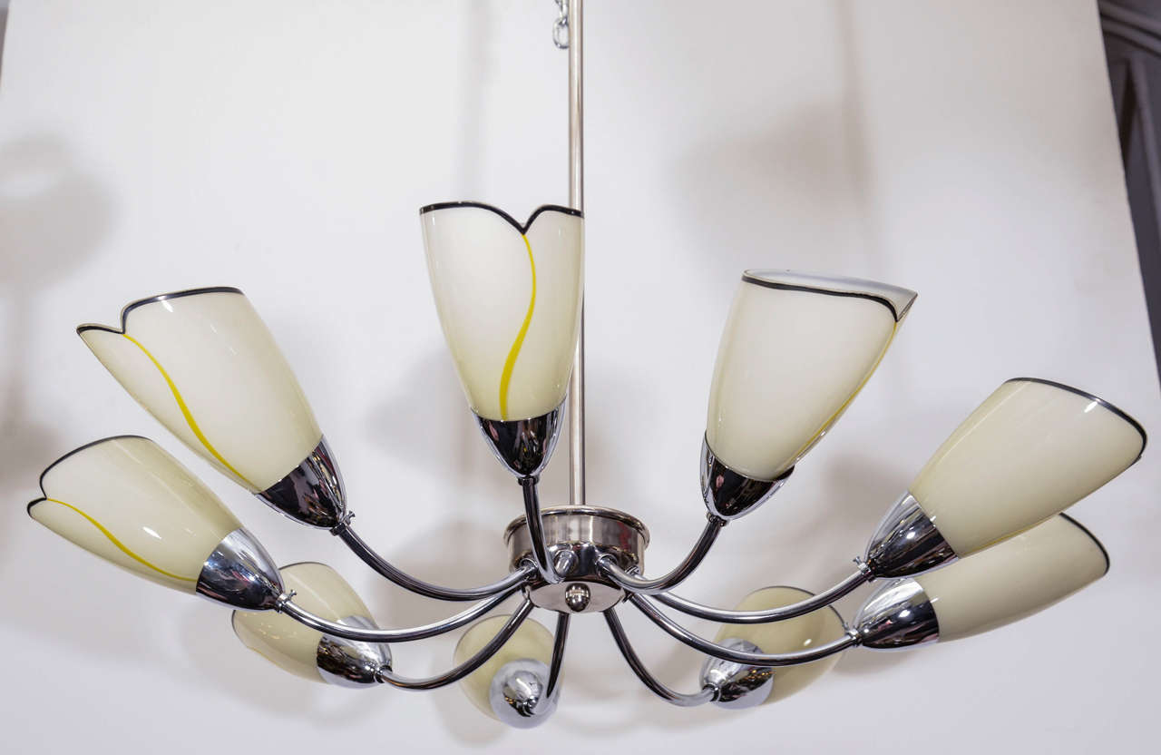 A chandelier in polished chrome with nine chrome arms and off-white flower-petal glass shades.