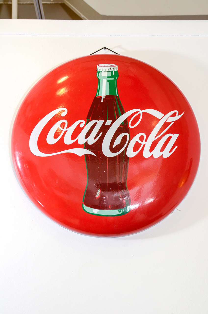 A vintage 1950's button style Coca Cola Sign made with porcelain over steel.