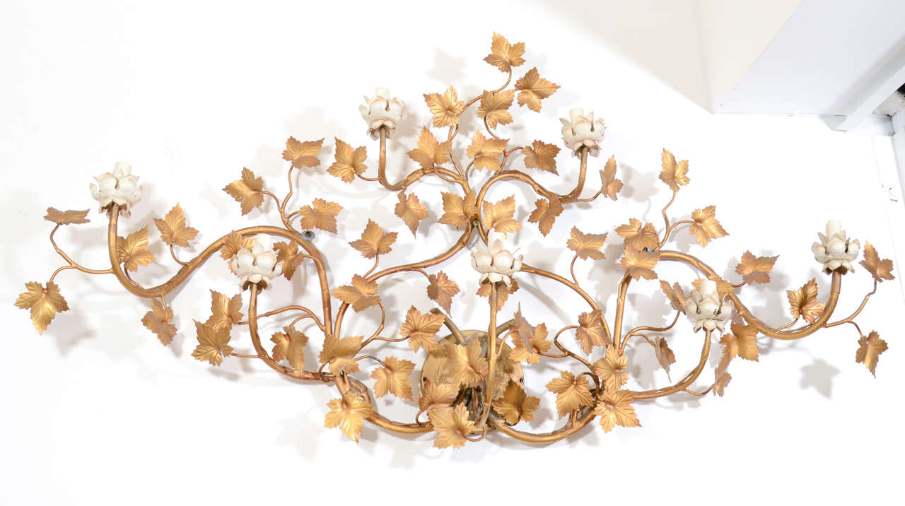 A vintage wall sconce with five lights decorated with floral motif of vines and leafs.