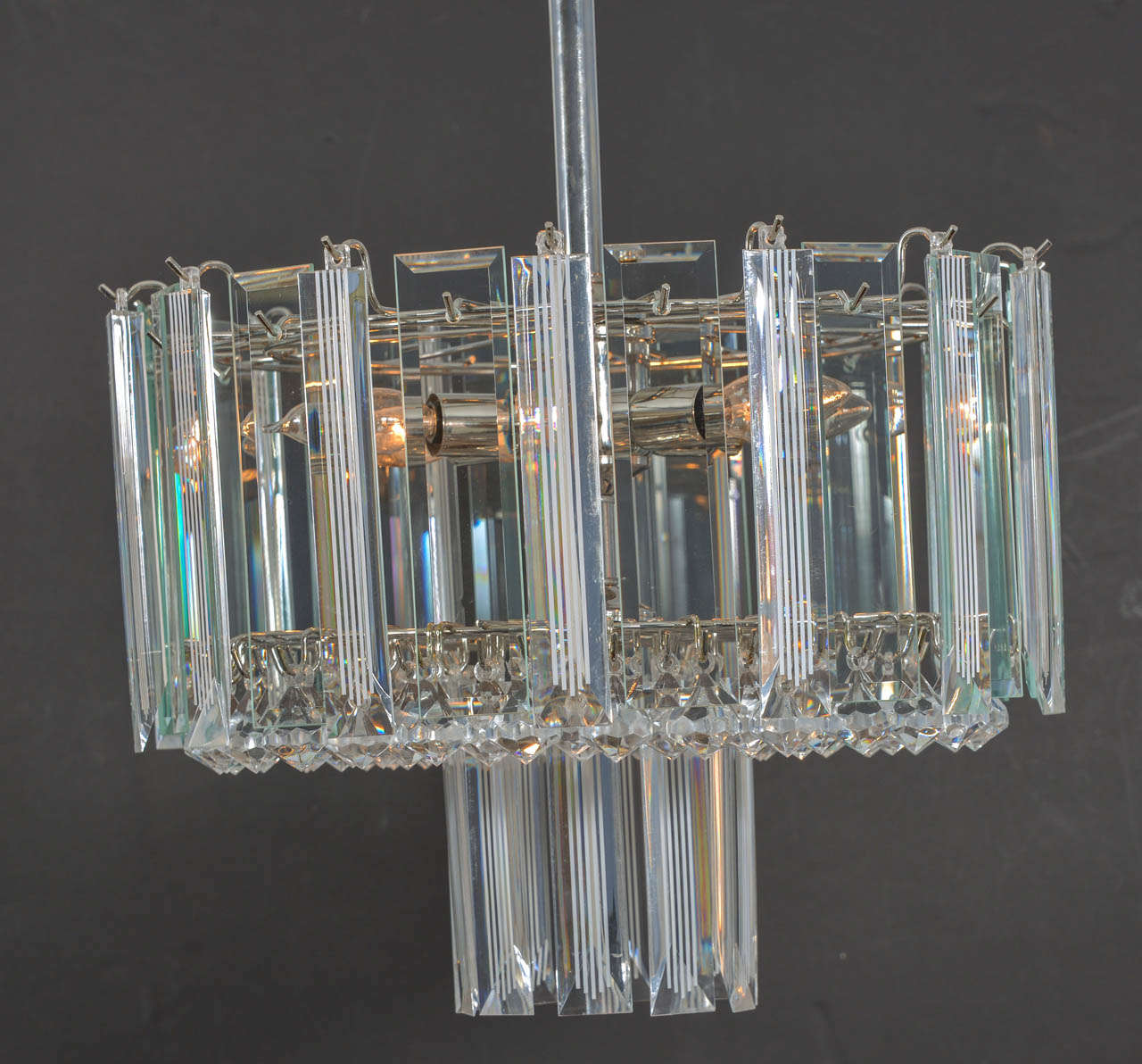 Six-light Mid-Century Modern Lucite chandelier with alternating panels of clear Lucite and decorated stripped Lucite and a bed of small kite shaped pendants hanging from the bottom of the chandelier all hanging from a brass plated frame. A