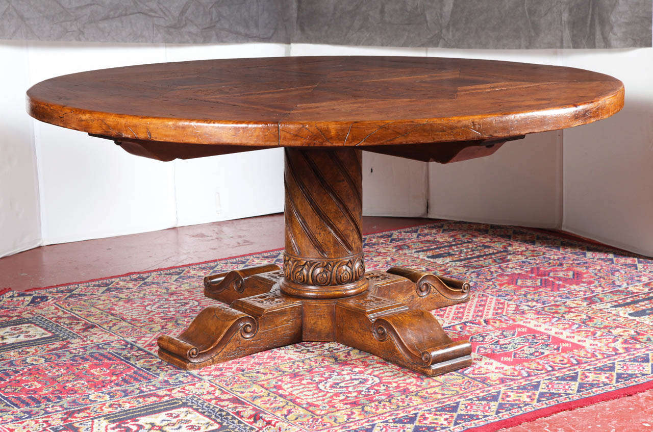 Large walnut round table from the French Pyrenees made with 18th century wood and base. The top comprises old parquet flooring in walnut, oak, chestnut and burl walnut. The base features intricate carving.