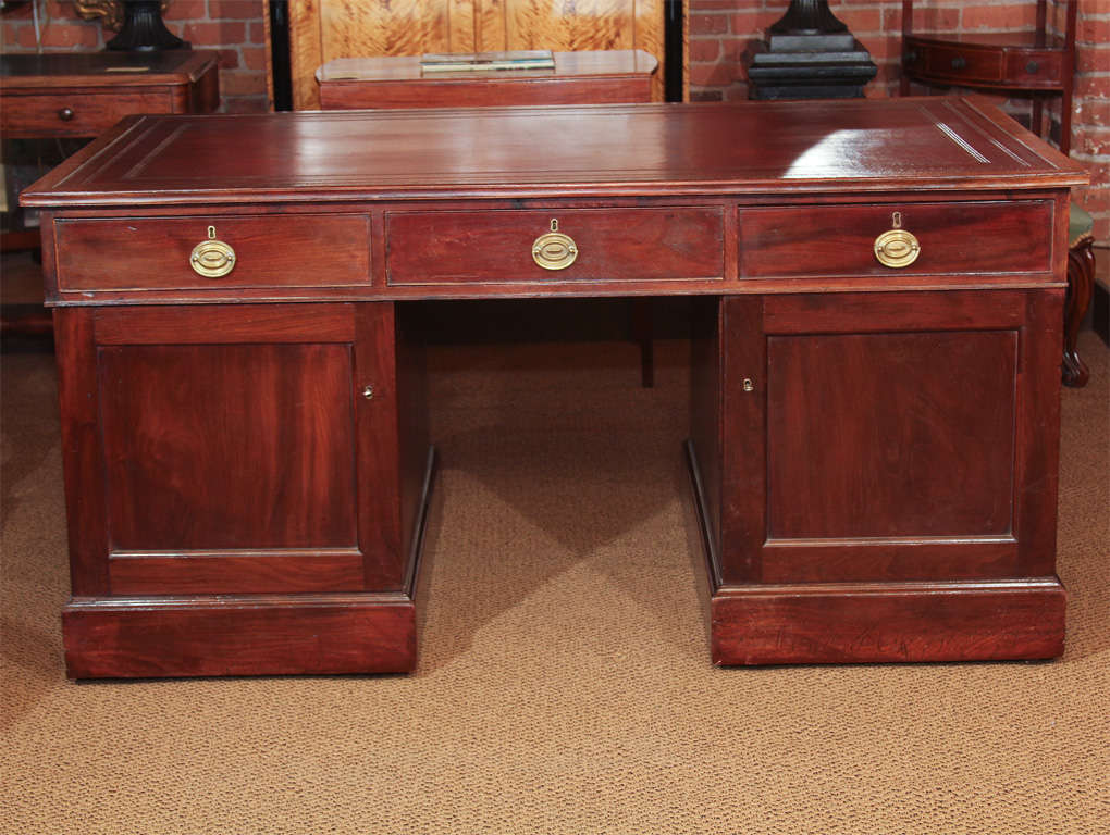 English Georgian Partners Desk

This is an English mahogany, George III partners desk with a new tooled leather top. The leather is a rich maroon color.

It features six original dove-tailed drawers (three on each side). The rails are mahogany