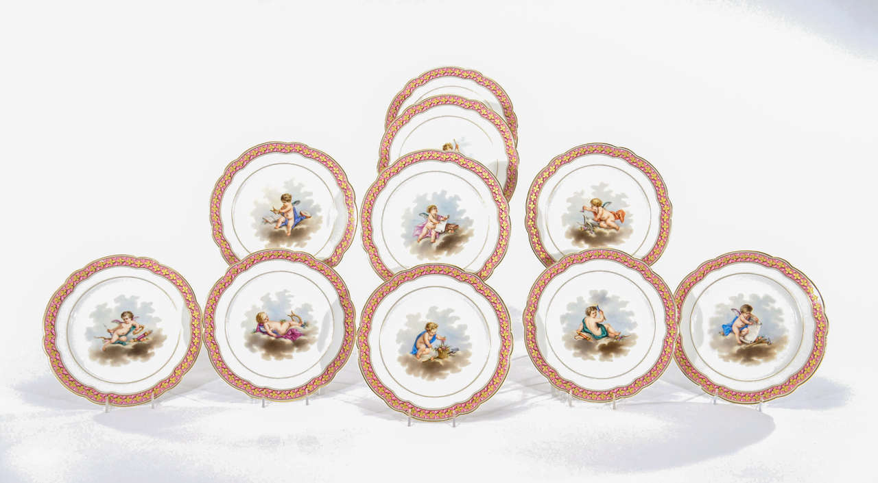 A lovely set of 10 hand painted cabinet plates with Rose DuBarry enameled border on shaped rims all highlighted in gold. The uniquely painted centers are all well-executed in fine detail, depicting various angels and putti on cloud-like backgrounds.