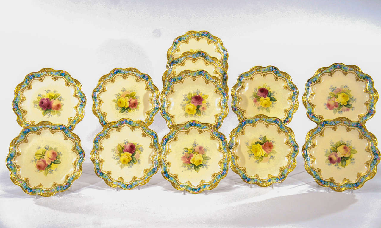 This set of 12 dessert plates feature hand painted rose subjects on an ivory ground, all beautifully painted and incorporating the natural colors of the botanical species.
 The exqusitely shaped borders create another layer of decoration by framing