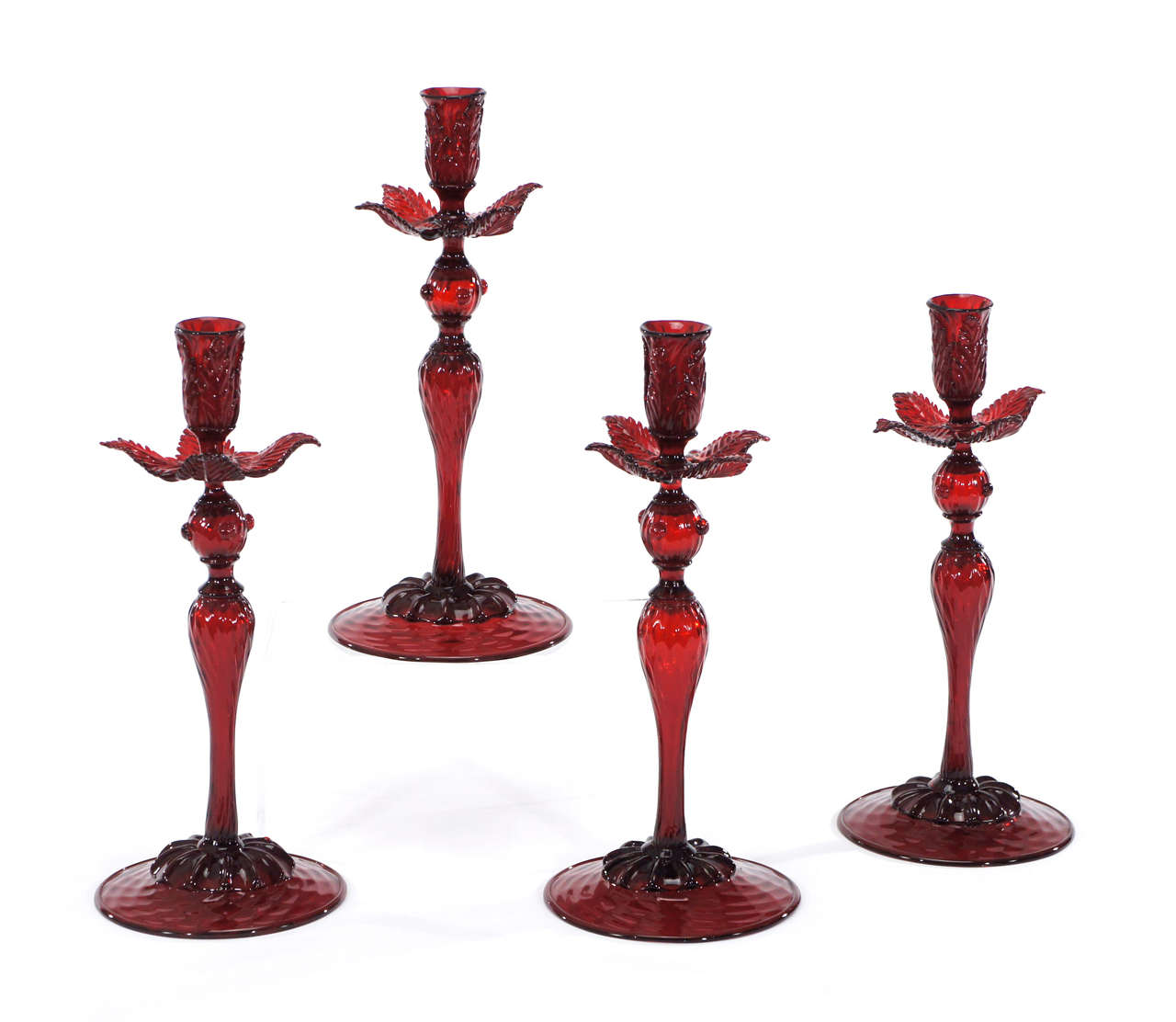 An amazing grouping of 4 matching candlesticks for a dramatic table setting. Two sets of 2 hand blown ruby glass tall candlesticks with quilted optic decoration in the foot, ribbed up to the connectors with applied leaves forming the bobeches.