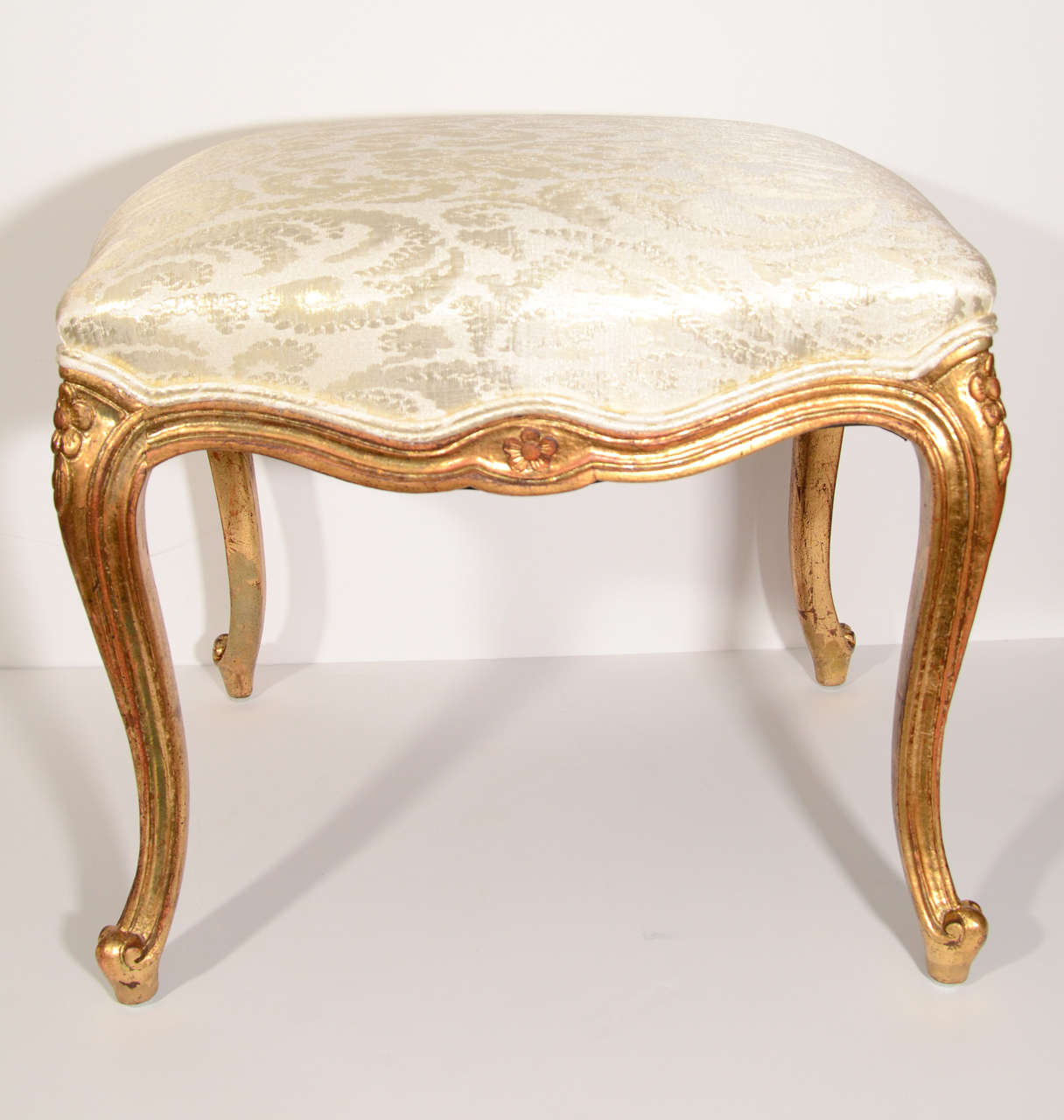 Beautiful Louis XV style bench with antiqued gilt wood base and legs. The legs are hand carved with fluted design and floral details. Newly upholstered in scalamandre silk fabric with gold damask print.  There are two benches available and can also