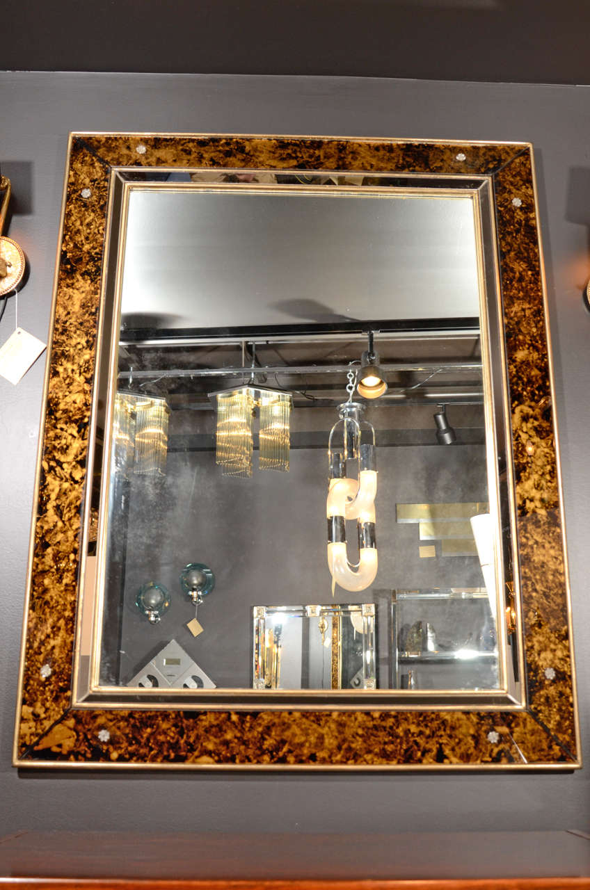 Exquisite shadowbox mirror with tortoise colored glass outer borders and with smoked mirrored inset borders.  The mirror has  antiqued gilded wood frame and trim and rosette details on each corner.  Can be hung vertically as shown or horizontally.