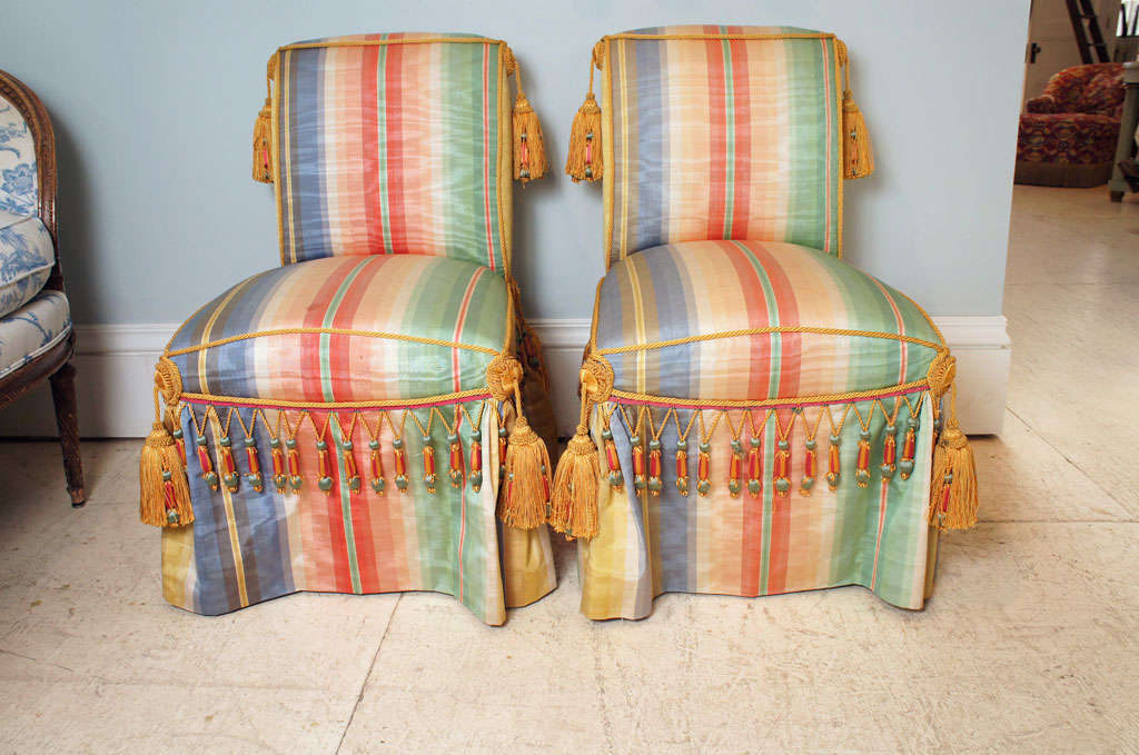 Set of two silk taffeta upholstered slipper chairs each fitted with tassels and elaborate
fringe.  A third chair is also available