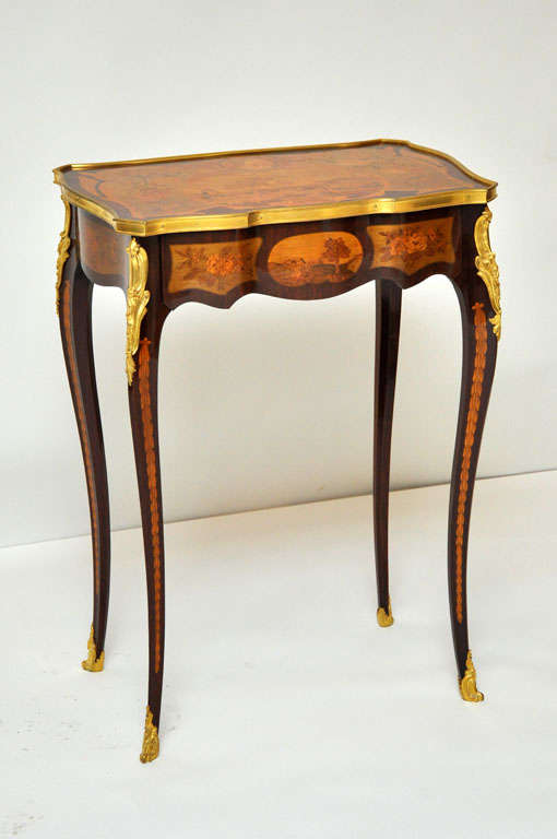 Unique transitional style marquetry occasional table or gueridon after a model by David Roentgen. Gilt banded shapely marquetry top surface depicting a farm scene with animals and herdsman, below a shapely floral marquetry frieze containing a hidden
