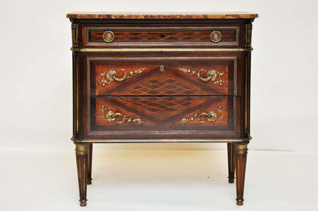French Louis XVI style chest of drawers or commode after a model by Jean-Henri Riesener, with its petite portions will fit comfortably into small spaces. The top drawer is smaller with geometric parquetry design, the two lower drawers with shared