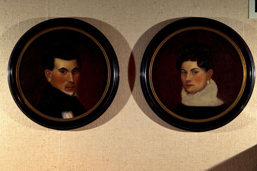 This stern couple peers out at us through unique porthole frames from the period. Painted on canvas, they have been re-stretched onto wood backing and retrofitted to these frames, looking none the worse for the wear--though perhaps it was the move