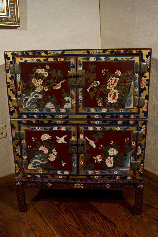 This three-piece, painted and lacquered chest in a rich umber color features birds and botanical foliage on four exterior sides and a deep black lacquer on the interior. The colorfully depicted birds and butterflies flitting about make the surface