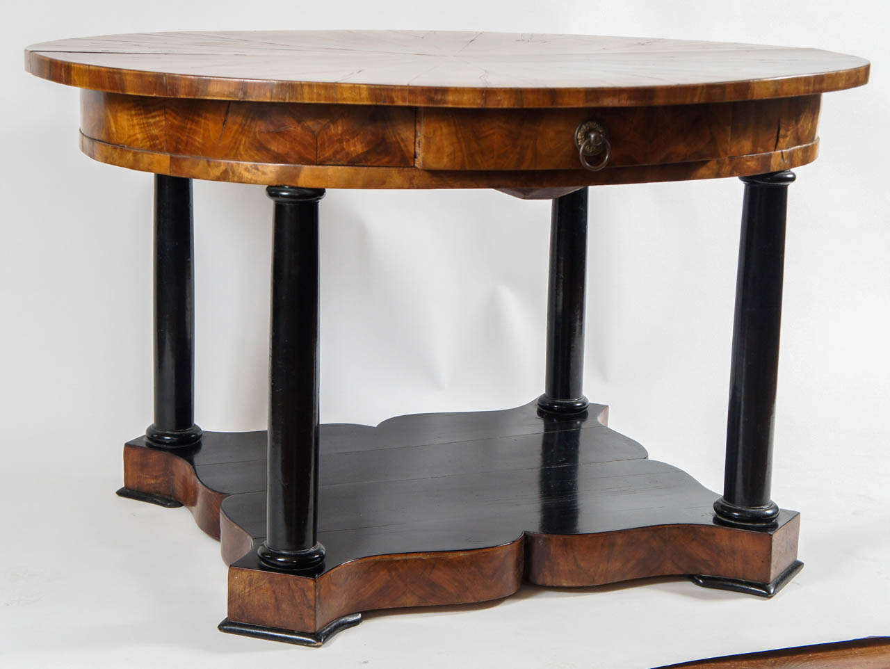 Außergewöhnlicher, ovaler Biedermeier-Tisch aus Nussbaum um 1830 mit einer exquisiten Furnierplatte mit Strahlenmuster und einer einzigen durchgehenden mittleren Schublade über ebonisierten dorischen Kolonettenstützen auf einem Sockel mit Höckern.