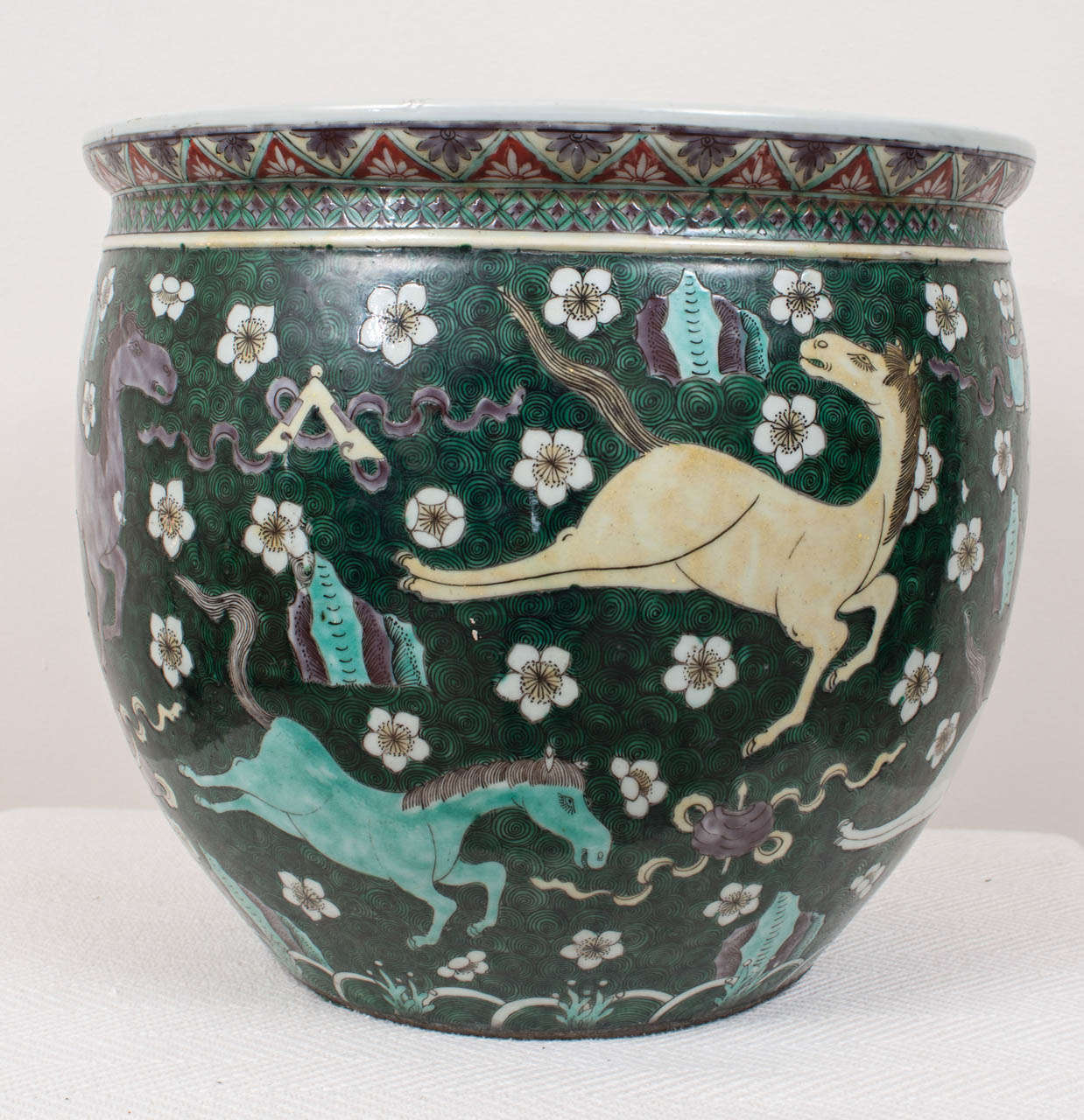 Unusual decoration of galloping horses; gorgeous color palette of deep leaf green, aubergine, turquoise, and ecru.