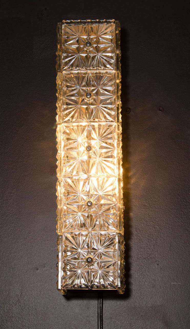 Pair of elegant mid century modern sconces with three dimensional rectangular form. The sconces are comprised of three sides of faceted crystal blocks or insets with starburst designs.  The sconces have chromed backplates and fittings on the top and