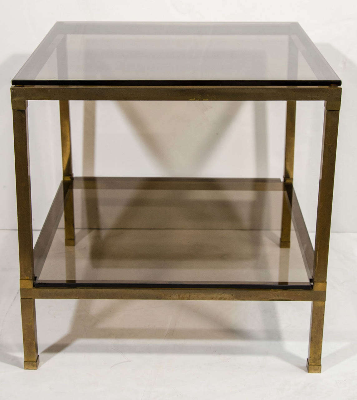 Pair of mid century modern end tables with two tier design in dark patinated brass metal with dense smoked bronze glass tops. The end tables have a great weight to them and have wonderful cube forms. Make great night stand option.