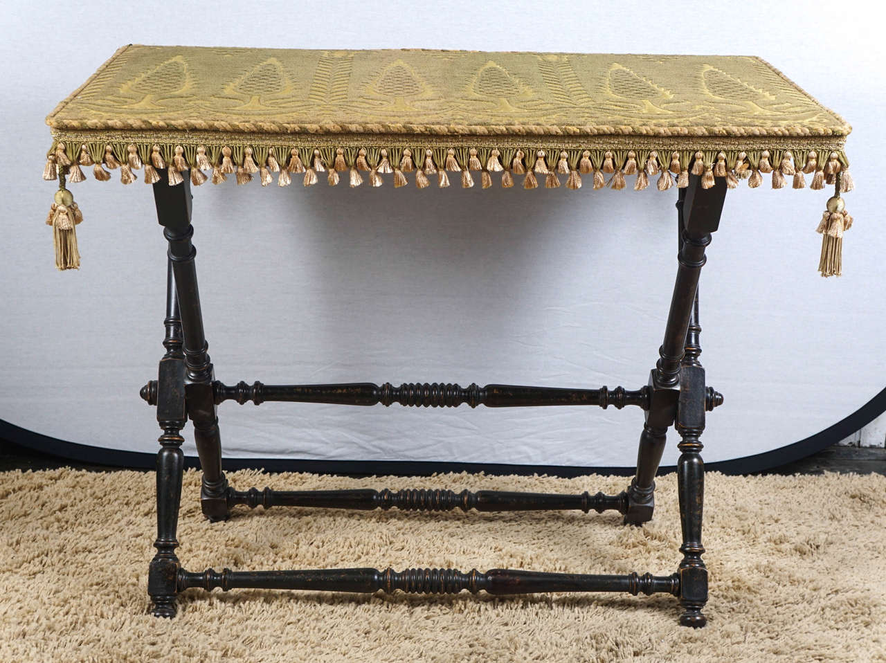 This fine table made from turned and carved wood in a rich black stain is from France and was made during the late 19th century. The top is covered in green cut velvet fabric with companion trims in and old faded green and cream. The fabric laid