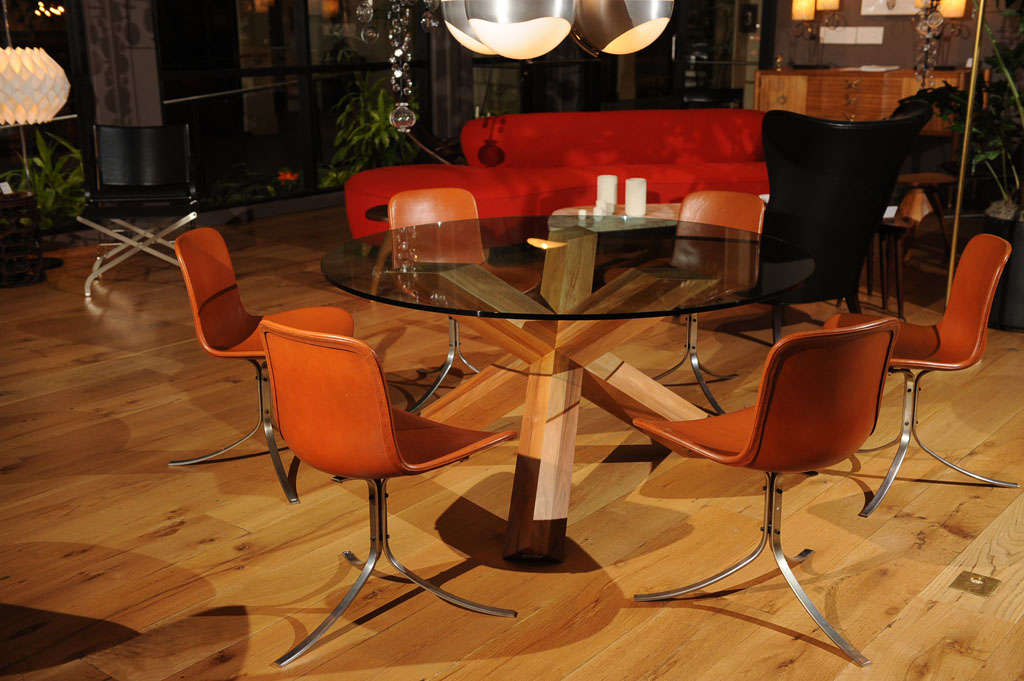 A mortise and joint assembly base made of walnut supporting a round glass table top. Designed by Mario Bellini for Cassina, partial sticker remains.