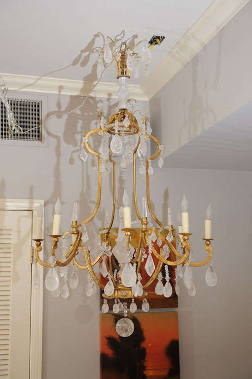 Mid 20th century grand scale French eight arm gilt bronze neoclassical style rock crystal  chandelier of open cage form. The elaborate corona with carved rock crystal. Center supporting crystal tier drops above a beaded crown. The carved center