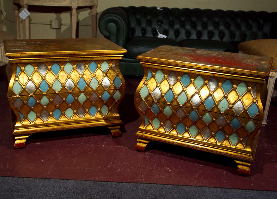 Pair of distress-gilded and painted bombe chests, 20th century in the Hollywood Regency style, each has two drawers with checkerboard-pattern decoration.