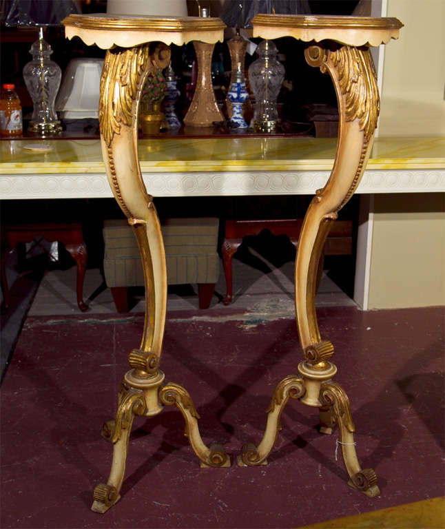 Pair of Creme Peinte and parcel-gilt French Rococo style pedestals, each has a scalloped top supported by a scroll like pedestal headed by foliate carving, raised on splayed tripod bases.