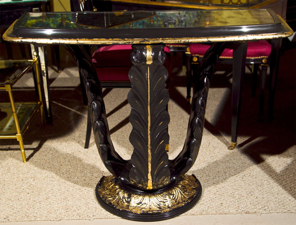 Intriguing console table, circa 1940, overall ebonized and parcel-gilt, the D-form top with smokey glass top, supported by three plume columns on block base. By Jansen.